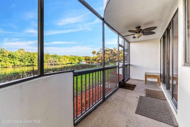 unfurnished sunroom featuring ceiling fan and a water view