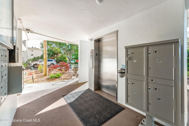 doorway featuring elevator, lofted ceiling, and a mail area