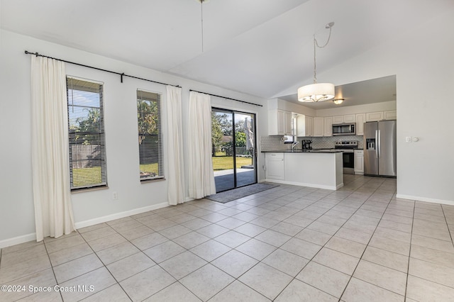 kitchen featuring lofted ceiling, light tile patterned floors, white cabinetry, kitchen peninsula, and stainless steel appliances