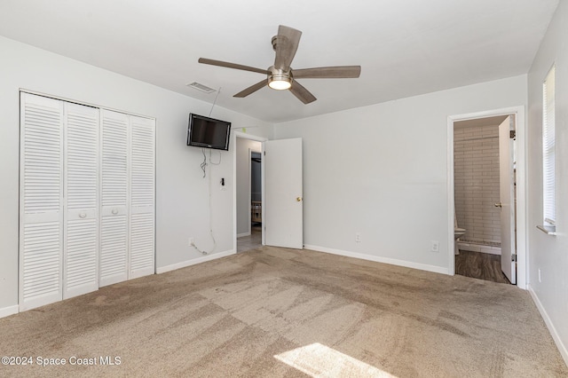 unfurnished bedroom featuring carpet flooring, ensuite bath, ceiling fan, and a closet