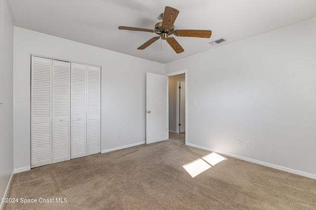 unfurnished bedroom with ceiling fan, light carpet, and a closet