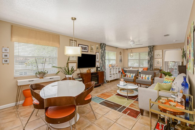 living room featuring ceiling fan, light tile patterned flooring, and a textured ceiling