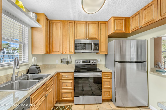 kitchen featuring sink, light tile patterned floors, plenty of natural light, and appliances with stainless steel finishes