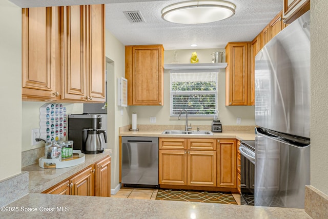 kitchen with a textured ceiling, light tile patterned flooring, sink, and appliances with stainless steel finishes