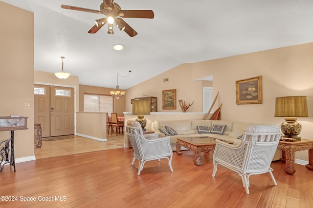 living room with ceiling fan with notable chandelier, light hardwood / wood-style flooring, and lofted ceiling