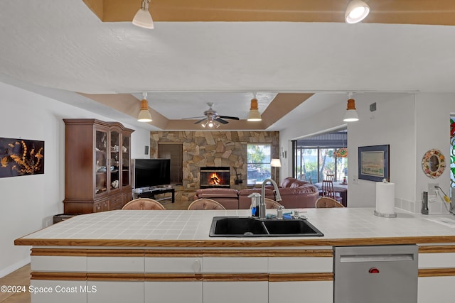 kitchen with tile countertops, white cabinetry, stainless steel dishwasher, and sink