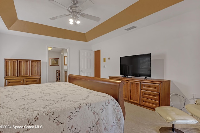 bedroom with carpet flooring, ceiling fan, and a tray ceiling