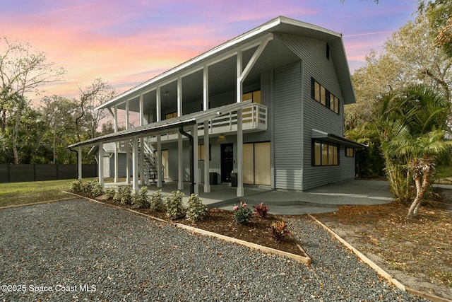 back house at dusk with a patio area and a balcony