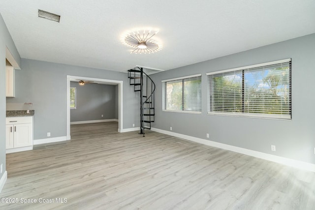 unfurnished living room featuring ceiling fan, light hardwood / wood-style flooring, and a textured ceiling