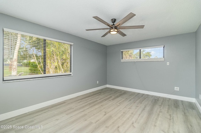 empty room with ceiling fan, light wood-type flooring, and a textured ceiling