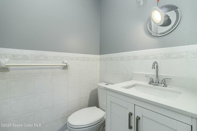 bathroom with vanity, tile walls, and toilet