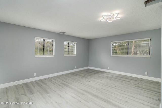 spare room with a textured ceiling and light wood-type flooring