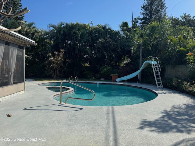 view of pool with a water slide, a patio, and an in ground hot tub