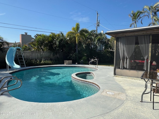 view of swimming pool featuring a patio, an in ground hot tub, and a water slide