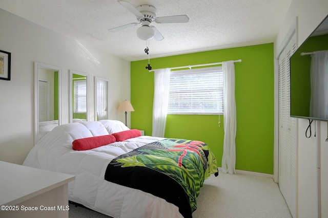 bedroom featuring ceiling fan, light colored carpet, and a textured ceiling