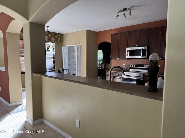 kitchen featuring dark brown cabinets, stainless steel appliances, a wealth of natural light, and light tile patterned flooring