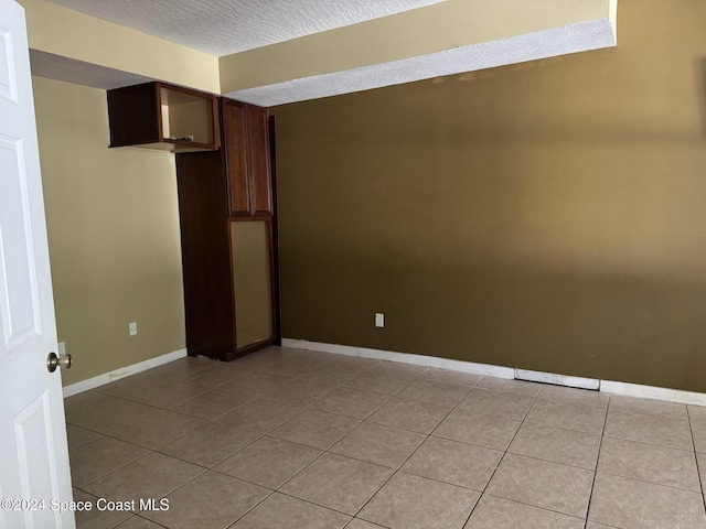 tiled spare room with a textured ceiling