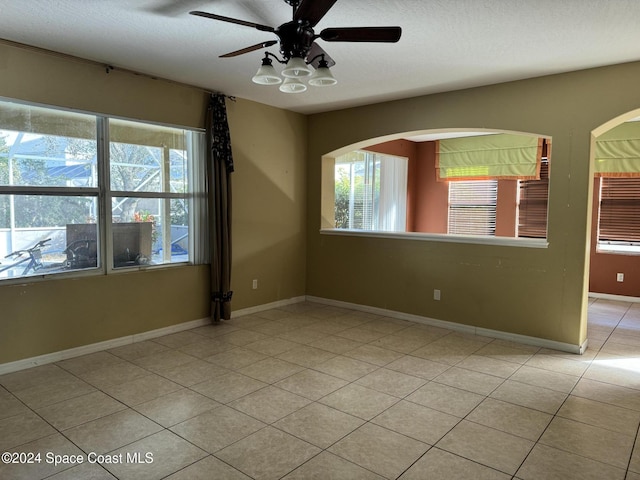 spare room with a textured ceiling, ceiling fan, and light tile patterned flooring