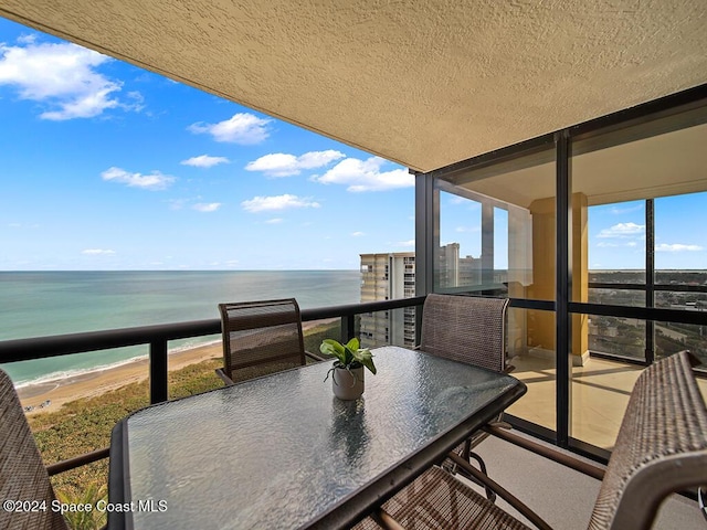 balcony with a water view and a view of the beach