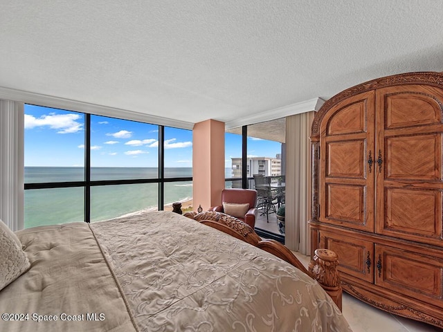 bedroom with expansive windows, a water view, and a textured ceiling