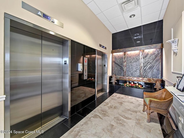 bathroom featuring elevator, a drop ceiling, and a towering ceiling