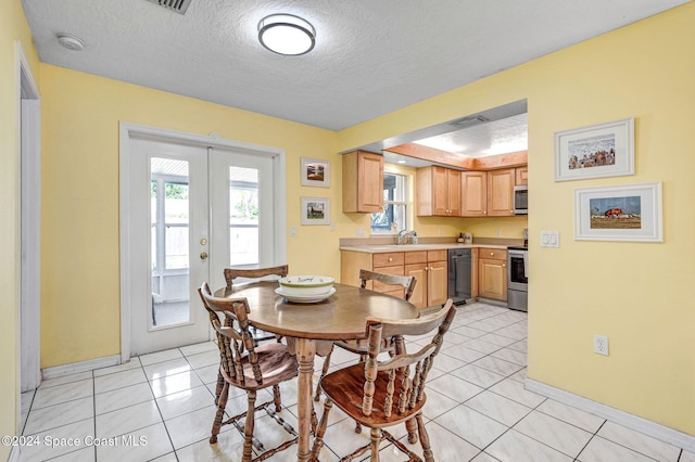 tiled dining space with french doors, a textured ceiling, and sink