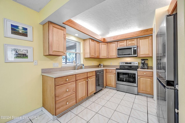 kitchen featuring light brown cabinetry, sink, stainless steel appliances, and a textured ceiling