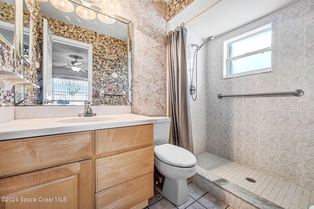 bathroom with ceiling fan, curtained shower, tile patterned floors, toilet, and vanity