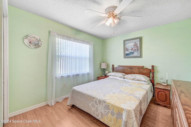 bedroom featuring ceiling fan, light hardwood / wood-style floors, and a textured ceiling