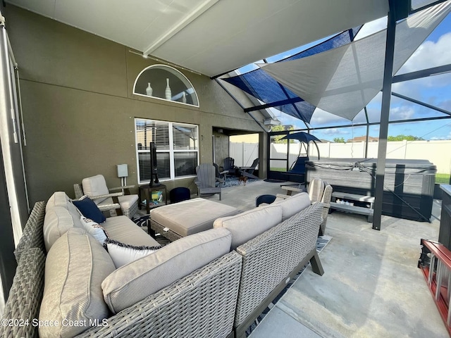 view of patio featuring glass enclosure, a fenced backyard, outdoor lounge area, and a hot tub