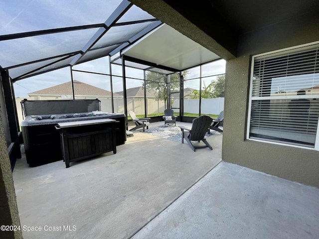 view of patio with glass enclosure, a hot tub, and fence