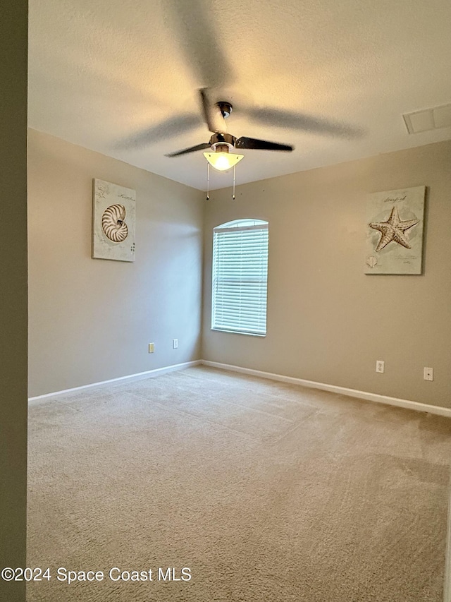 empty room with a textured ceiling, ceiling fan, visible vents, and baseboards