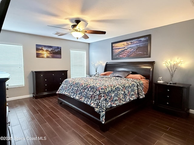 bedroom with a ceiling fan, visible vents, baseboards, and wood finished floors