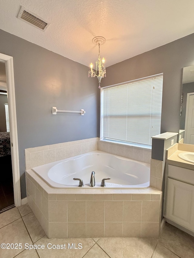 bathroom with a textured ceiling, vanity, visible vents, a bath, and an inviting chandelier