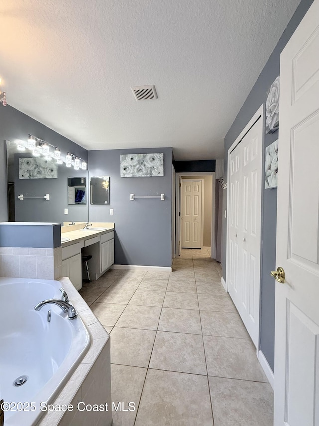 bathroom featuring visible vents, tile patterned floors, a textured ceiling, vanity, and a bath