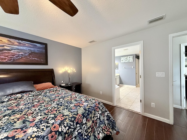 bedroom with visible vents, dark wood finished floors, a textured ceiling, and baseboards