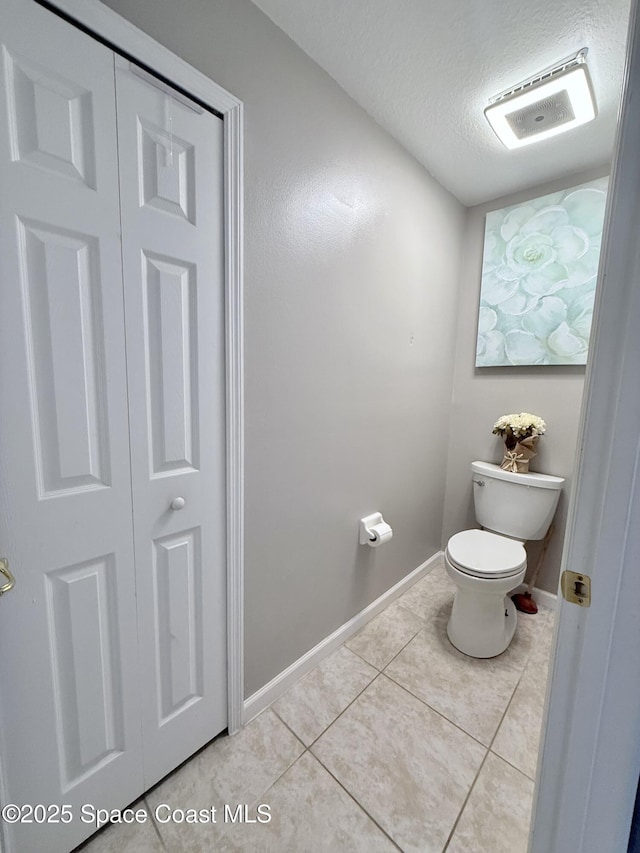 bathroom featuring tile patterned flooring, baseboards, a textured ceiling, and toilet