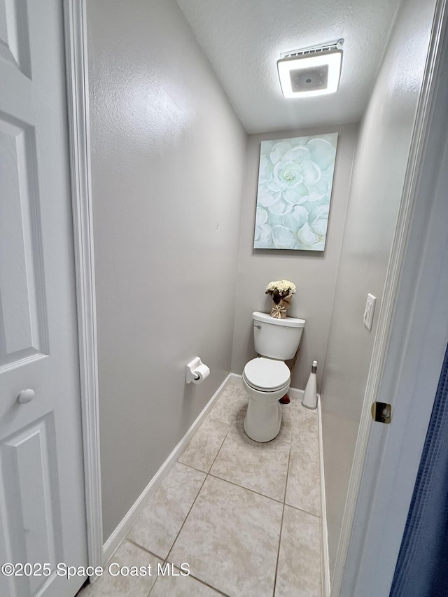 bathroom featuring tile patterned flooring, baseboards, a textured ceiling, and toilet