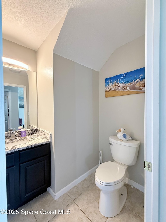 bathroom featuring toilet, vanity, a textured ceiling, tile patterned flooring, and baseboards