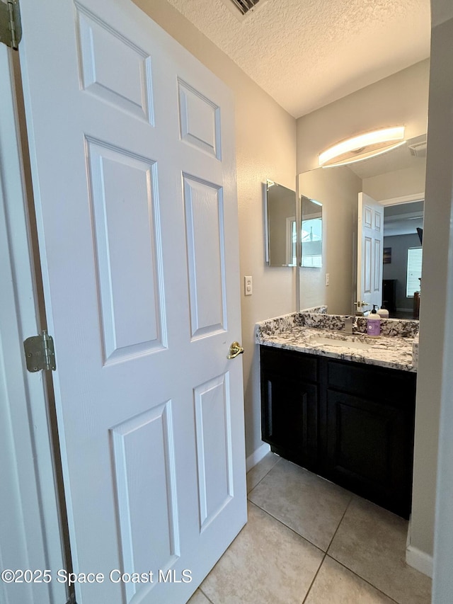 bathroom featuring vanity, baseboards, a textured ceiling, and tile patterned floors