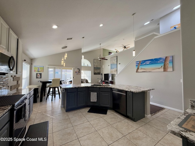 kitchen with appliances with stainless steel finishes, lofted ceiling, light tile patterned flooring, and a sink