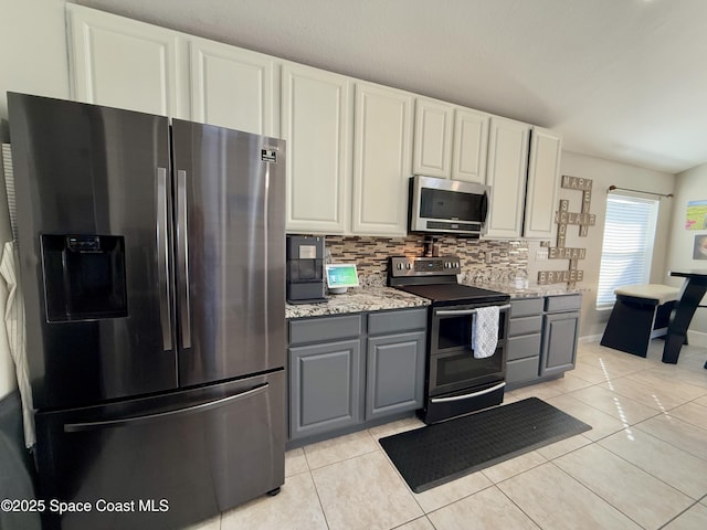 kitchen featuring gray cabinetry, appliances with stainless steel finishes, light tile patterned flooring, and tasteful backsplash