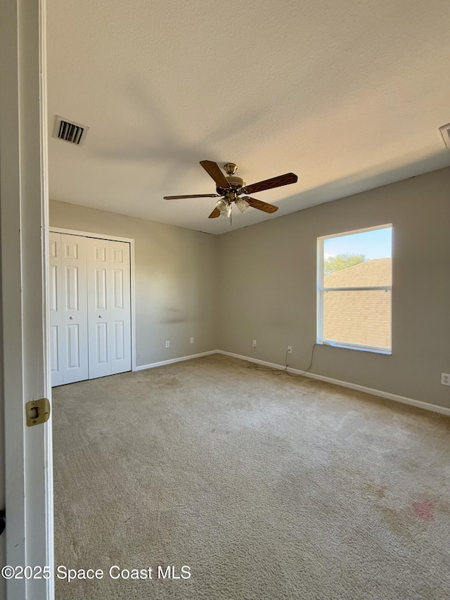 unfurnished bedroom with carpet, a closet, visible vents, and a textured ceiling