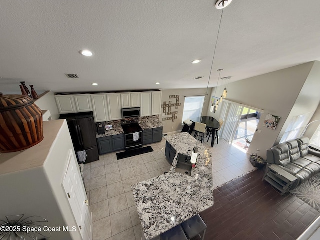 kitchen with light stone counters, stainless steel appliances, white cabinets, backsplash, and pendant lighting