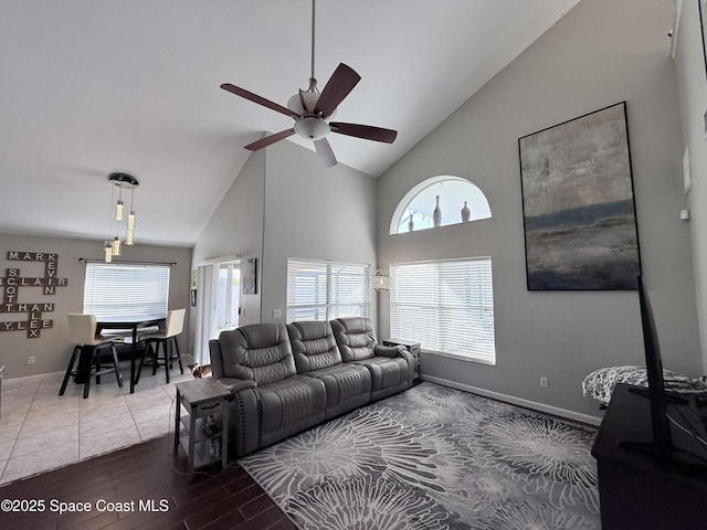 living area featuring ceiling fan, high vaulted ceiling, wood finished floors, and baseboards