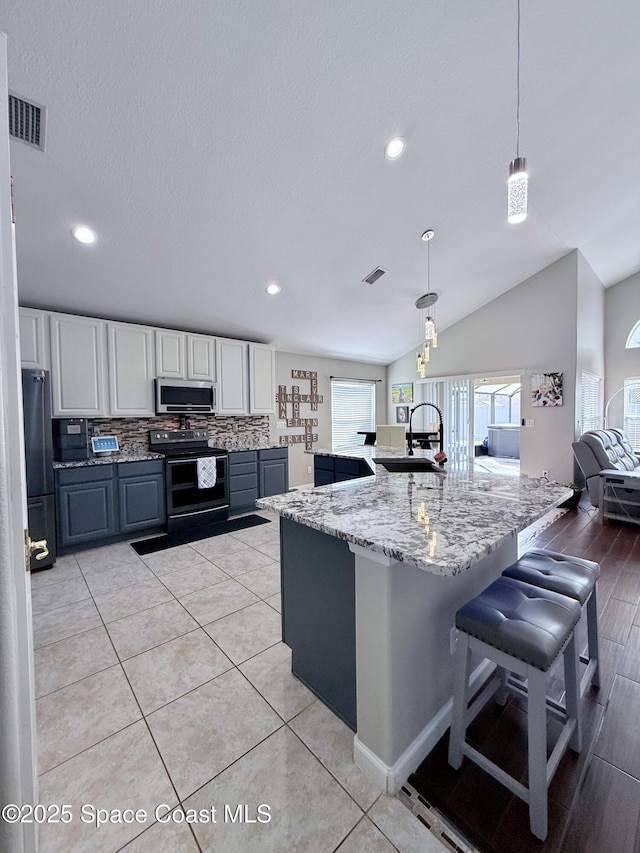 kitchen with stainless steel appliances, a sink, visible vents, and light stone countertops