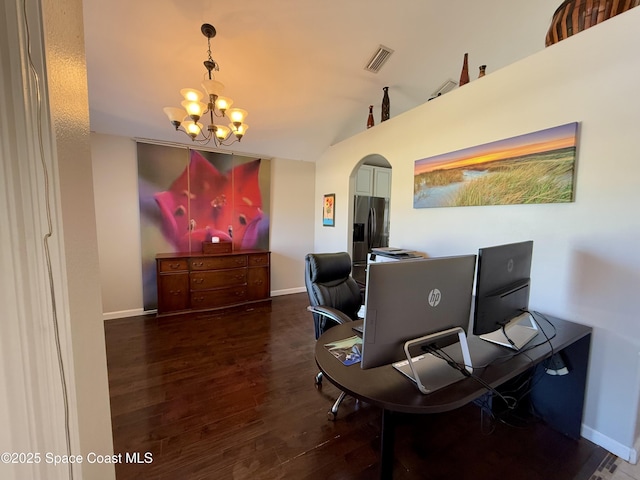 office area with arched walkways, wood finished floors, visible vents, and baseboards