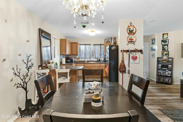 dining area featuring a textured ceiling, hardwood / wood-style flooring, and a notable chandelier