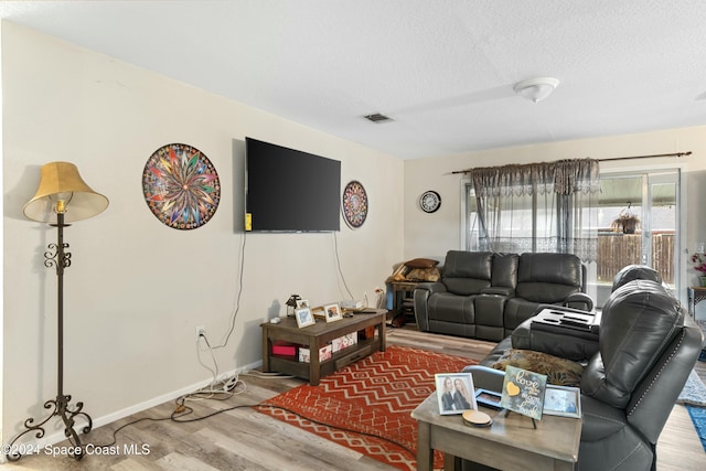 living room featuring wood-type flooring and a textured ceiling