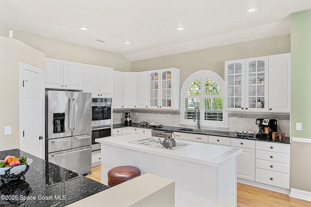 kitchen featuring stainless steel appliances, lofted ceiling, white cabinetry, and sink